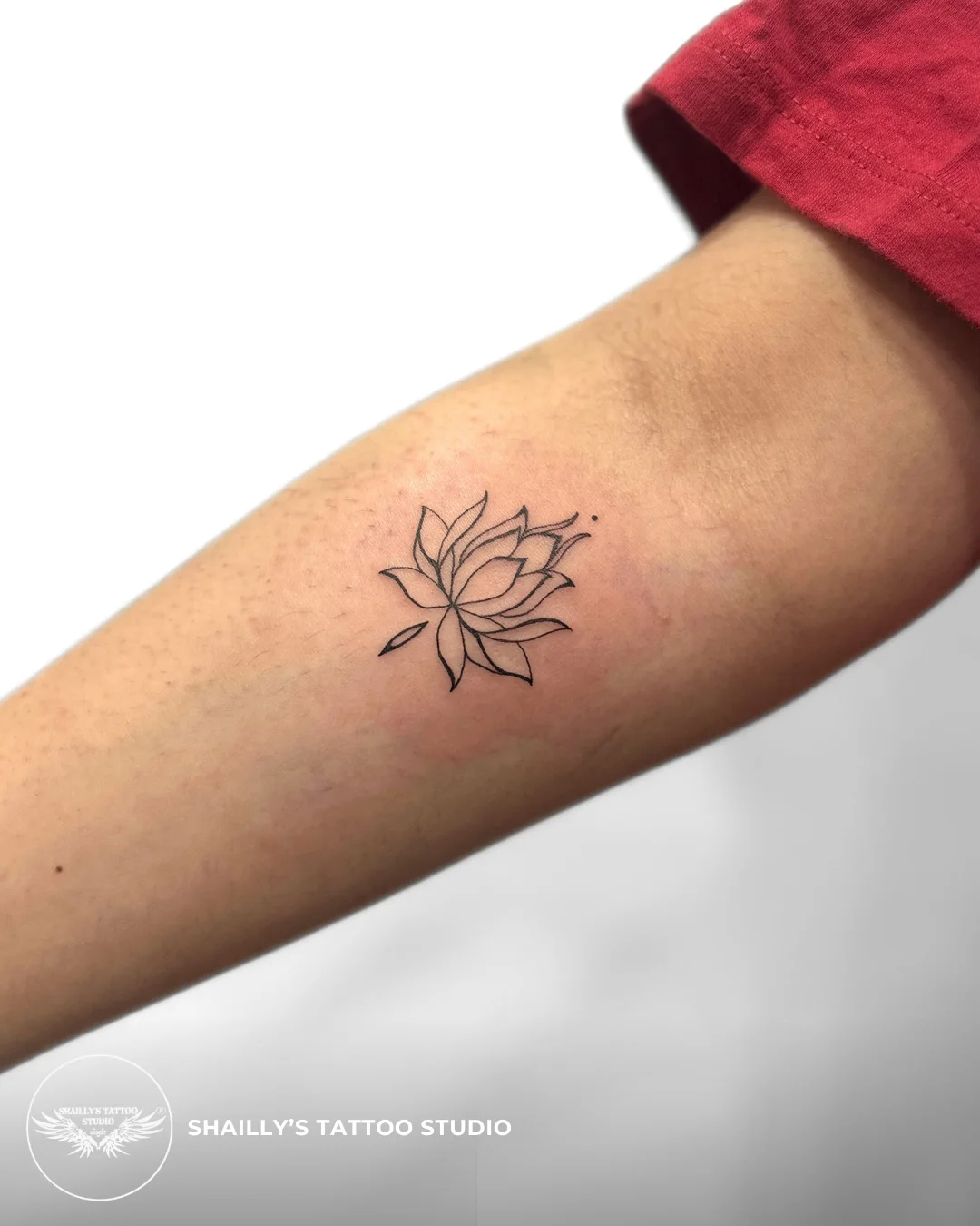 Small fine-line lotus tattoo on an arm